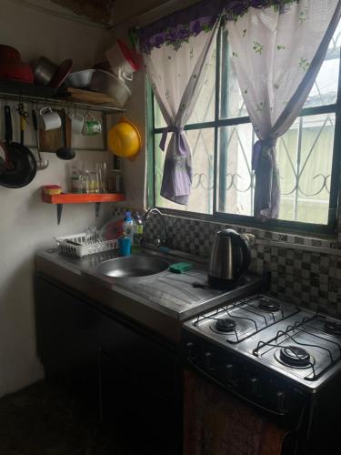 cocina con fogones, fregadero y ventana en Alojamiento Tres Lunas Triple, en Chuy