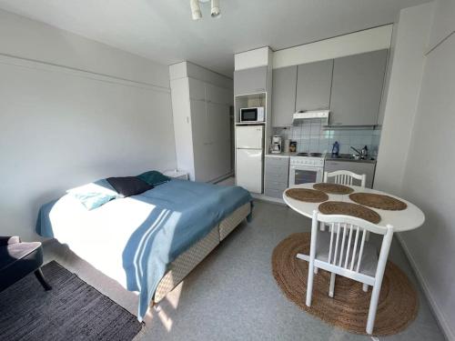 1 dormitorio con cama, mesa y cocina en Toimiva huoneisto kahdelle! Smart TV, Saimaanranta, nopea netti! en Lappeenranta