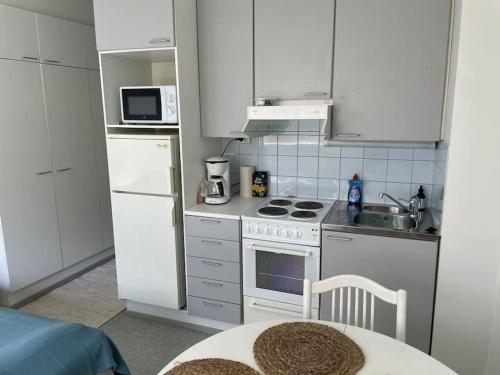 una cocina con armarios blancos y un horno de fogón blanco en Toimiva huoneisto kahdelle! Smart TV, Saimaanranta, nopea netti! en Lappeenranta