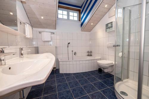 La salle de bains est pourvue d'un lavabo, d'une baignoire et de toilettes. dans l'établissement Alpenkönigin Fewo Lang, à Riezlern