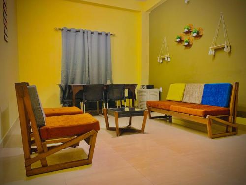 uma sala de estar com cadeiras, um sofá e uma mesa em Moonlight Homestay em Guwahati
