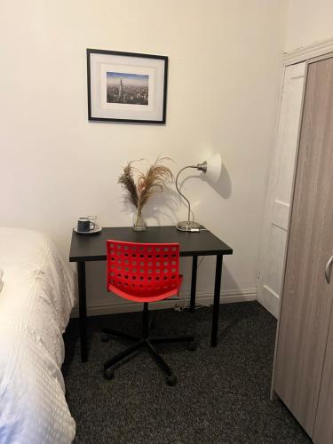 a desk with a red chair and a lamp on it at ChaRloHub 01 in Coventry