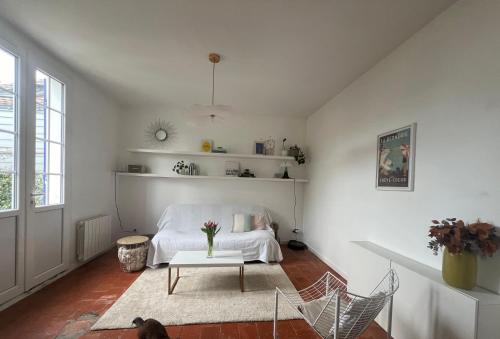 une chambre blanche avec un lit et une table dans l'établissement Maison typique - Crève-coeur, à La Bernerie-en-Retz