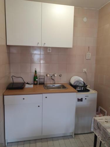 a kitchen with white cabinets and a sink at Apartman na najboljoj lokaciji , nedaleko od plaže in Bar
