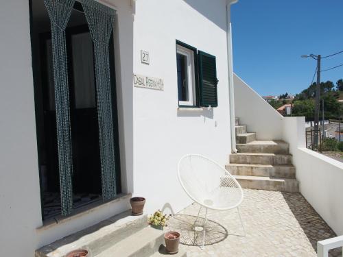 a white house with a white chair on a patio at Casal Regina in Sesimbra