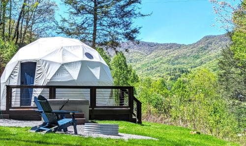 a yurt with a bench and a chair in the grass at Natures Dome @SmokyMountain in Sylva