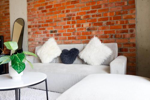 un sofá blanco con almohadas junto a una pared de ladrillo en Bachelor apartment in Cape Town, en Ciudad del Cabo