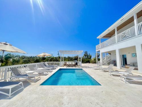 a villa with a swimming pool and chairs at The Better Life home in Governorʼs Harbour