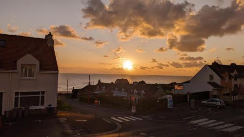 a sunset over a town with houses and the ocean at Coastal Breeze Apartment - Equihen-Plage in Équihen-Plage