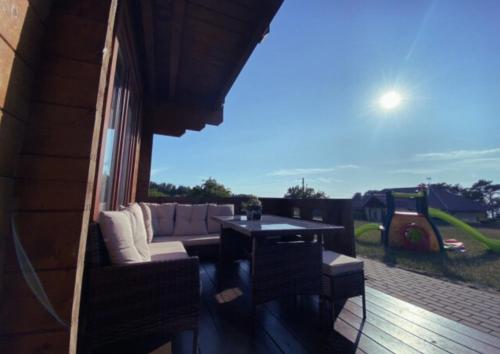 a patio with a couch and a table on a deck at Domek na Wzgórzu in Suchacz
