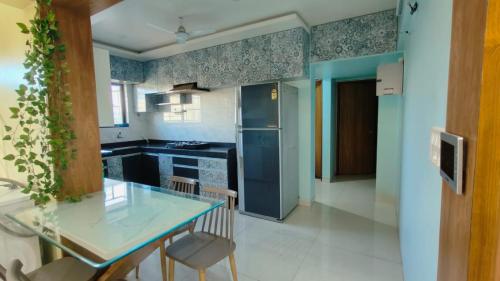 uma cozinha com uma mesa de vidro e um frigorífico azul em The ten - 2 rooms in 3bhk apartment em Pune