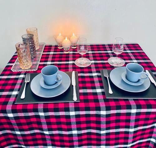 a table with a red and black checkered table cloth with plates and cups at Apartment cosy in Narok