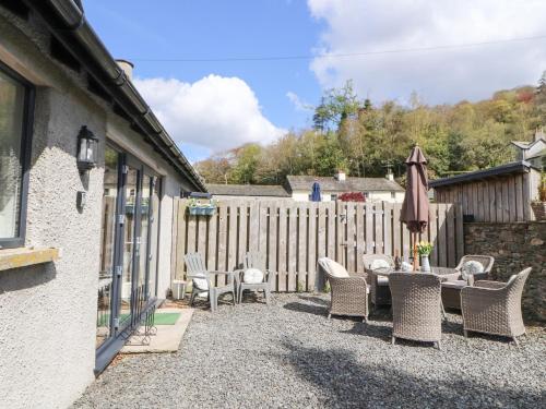 a patio with chairs and a table and an umbrella at Bishop Howe in Far Sawrey