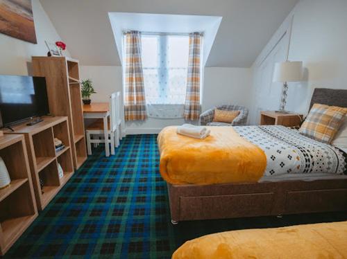a bedroom with two beds and a desk and a television at Nairn View Guest House in Nairn