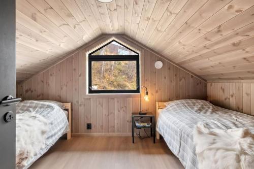 two beds in a room with a window at Hytte med fjellutsikt til nydelig natur in Sogndal