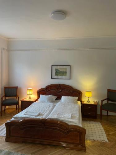 a bedroom with a bed with two chairs and two lamps at Kiskatona Vendégház in Balatonkenese