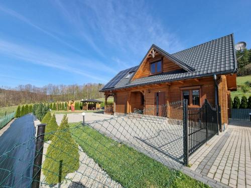 une maison en bois avec une clôture devant elle dans l'établissement Dom u Julii nad Strwiążem -Bieszczady, à Ustrzyki Dolne