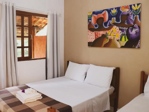 a bedroom with a bed and a painting on the wall at Pousada Donalu - Ótima Localização in Vale do Capao