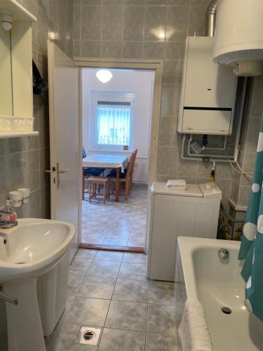 a bathroom with a sink and a tub and a table at Kiskatona Vendégház in Balatonkenese