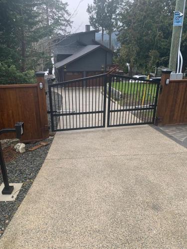 a gate to a driveway with a house at Water Front Home with Private Dock and Hottub in Sooke