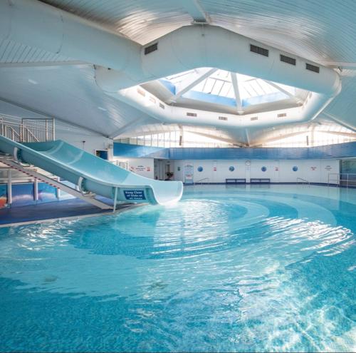 a large swimming pool with a slide in a building at Swift Holiday Caravan Rockley Park in Lytchett Minster