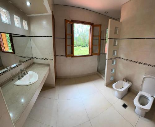 a bathroom with a toilet and a sink and a urinal at Cervantes - Casa de huespedes - Chacras de Coria in Ciudad Lujan de Cuyo