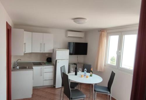 una cocina con mesa y sillas y una cocina con armarios blancos. en Apartmani Kalff, en Trogir