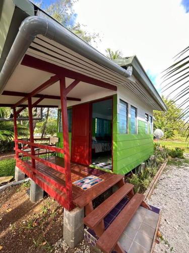 Puahua的住宿－LM Houses 2，一座带门廊的绿色和红色小房子