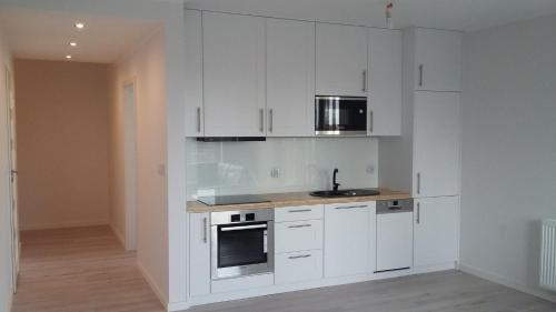 una cocina blanca con armarios blancos y fregadero en Apartament Baltica - Rezydencja Ustronie Morskie, en Ustronie Morskie