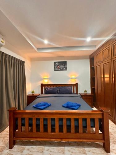 Un dormitorio con una gran cama de madera con almohadas azules en BT hotel Kata Beach, en Kata Beach