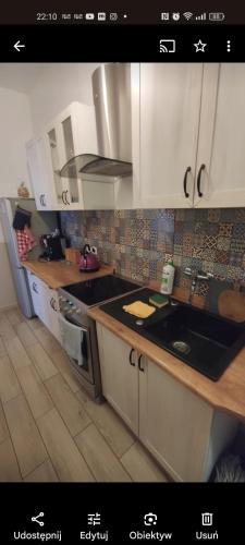 a kitchen with white cabinets and a sink and a stove at Night Host Trzebnicka 56/1 in Wrocław