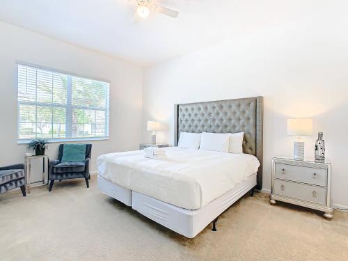 een witte slaapkamer met een groot bed en een stoel bij Experience Villa 12-Bed Vacation Haven BV368 in Kissimmee