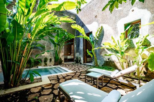 a garden with a pool and chairs and plants at Hacienda San Antonio Hool in Mérida