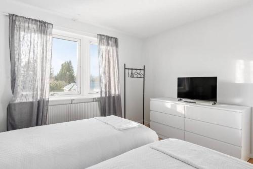 ein weißes Schlafzimmer mit 2 Betten und einem TV in der Unterkunft Bambinas Guest House Hässleholm in Hässleholm