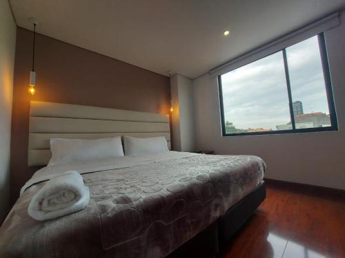1 dormitorio con cama y ventana grande en Suites and Apartments Bogotá, en Bogotá