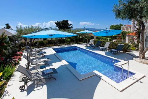 a swimming pool with chairs and umbrellas at Apartments Šemper - HEATED POOL in Bol