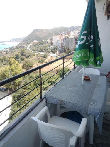 einen Balkon mit einem Tisch und einem Sonnenschirm in der Unterkunft إقامة عش الباز ساكت بجاية الجزائر in Taranimt