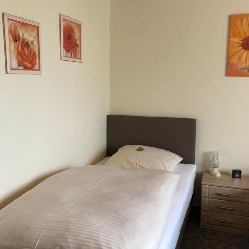 a bedroom with a white bed and a night stand at Landgasthof Fischer Veri in Mitterfels