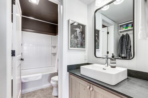 a bathroom with a sink and a toilet and a mirror at Chic Bend Condo with Fireplace and Forest Views! in Bend