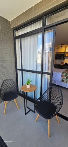a balcony with two chairs and a table and a bed at Flats Tramonto - By EasyHost in João Pessoa