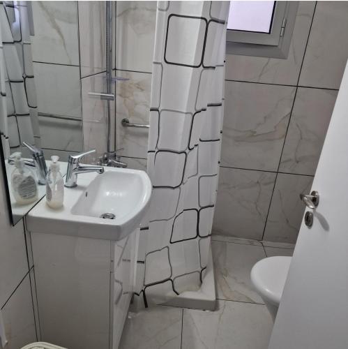La salle de bains blanche est pourvue d'un lavabo et d'une douche. dans l'établissement Cozy 1 bedroom apartment Larnaca city-center F, à Larnaka