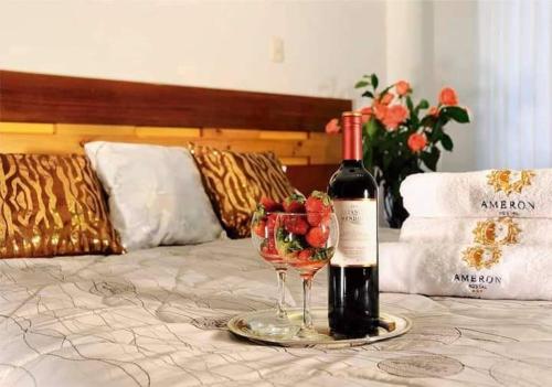 a bottle of wine and a wine glass on a bed at Hostal Ameron in Juliaca