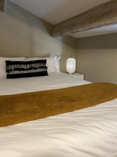 une chambre avec un lit avec des draps blancs et une lampe dans l'établissement Appartements St. Pancrace, à Corte
