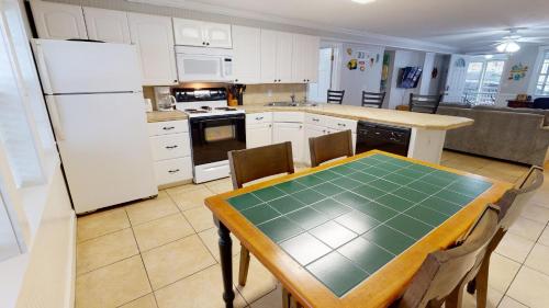 a kitchen with a table and a white refrigerator at Family Time Lower by Tybee Vacation Rentals in Tybee Island