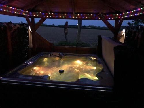 a jacuzzi tub with lights and a woman in the background at Couple’s Lodge With Hot Tub in Lincolnshire
