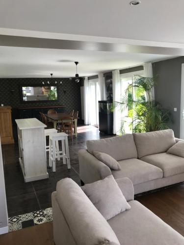 un salon avec deux canapés et une cuisine dans l'établissement L’Augustine, maison contemporaine à la campagne !, au Tilleul