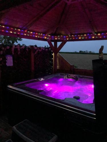 un bain à remous avec éclairage violet sous une tente dans l'établissement Couple’s Lodge With Hot Tub, à Lincolnshire
