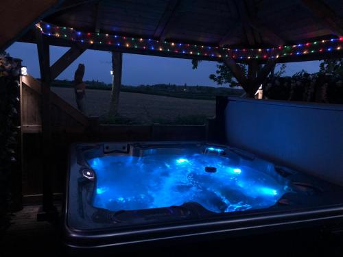 un bain à remous bleu éclairé dans une arrière-cour la nuit dans l'établissement Couple’s Lodge With Hot Tub, à Lincolnshire
