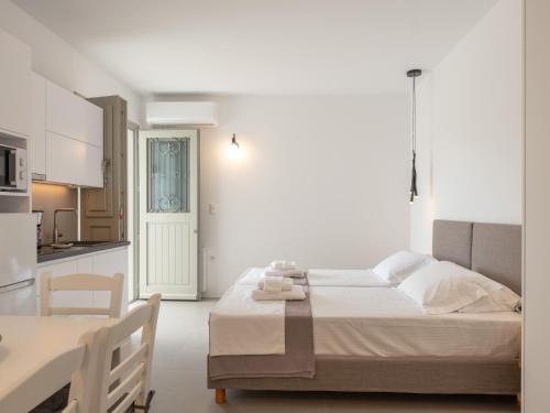 ein weißes Schlafzimmer mit Bett und Küche in der Unterkunft Studio Busho in Naoussa
