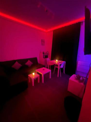 uma sala de estar com luzes cor-de-rosa, uma mesa e cadeiras em La Suite Liege em Seraing